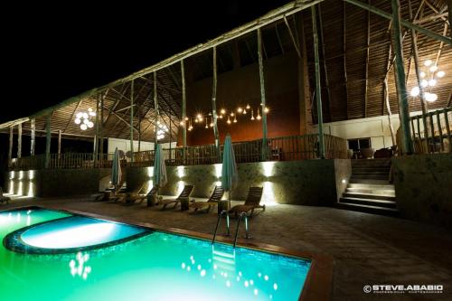 a swimming pool at night with chairs and umbrellas at Zaina Lodge in Mole
