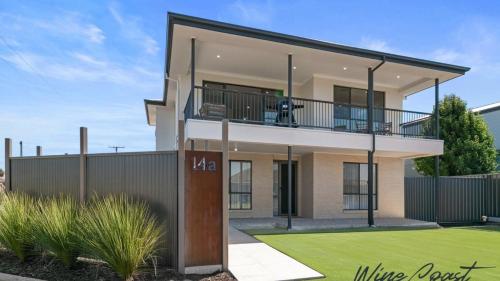 una casa con un cane seduto su un balcone di Mid Coast Surf & Vines By Wine Coast Holidays a Port Noarlunga South