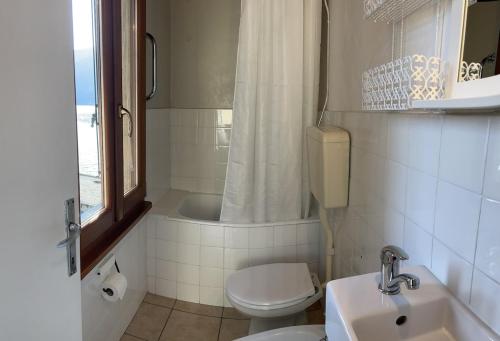 a bathroom with a toilet and a sink and a shower at Holiday Home by the Beach in Sala Comacina