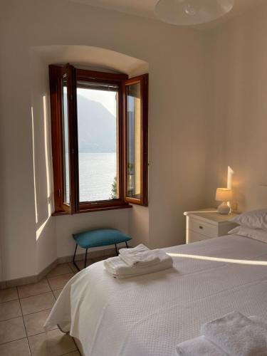 a bedroom with a window and a bed and a chair at Holiday Home by the Beach in Sala Comacina