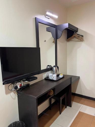 a black desk with a television and a mirror at Sera Sentosa Inn in Kampong Perin