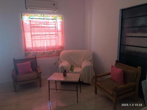 a living room with two chairs and a table and a window at Casa ilusión in Artilleros