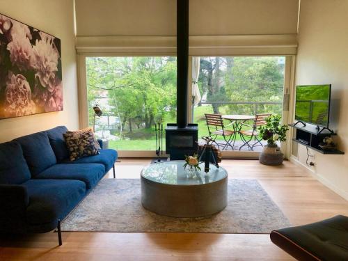 a living room with a blue couch and a coffee table at Daylesford Lake Villa1 Lake Frontage pet friendly in Daylesford