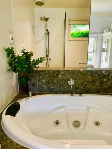a white bath tub in a bathroom with a mirror at Daylesford Lake Villa1 Lake Frontage pet friendly in Daylesford