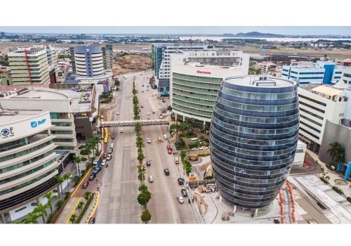 an aerial view of a city with a tall building at Ecuabook Wyndham Garden Torre Sol 907 in Guayaquil