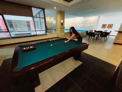 a woman playing pool in a room with a pool table at Ecuabook Wyndham Garden Torre Sol 907 in Guayaquil