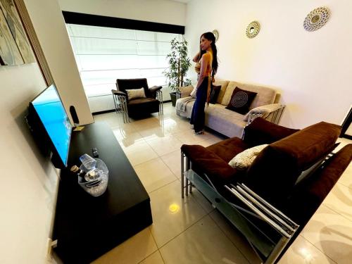 a woman is standing in a living room at Ecuabook Wyndham Garden Torre Sol 907 in Guayaquil