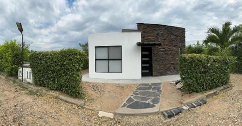 a small white and black house on a gravel road at Casa de campo D&G in Carmen de Apicalá