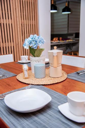 a table with plates and cups and a vase with flowers at Hogar de Olas Huanchaco in Huanchaco