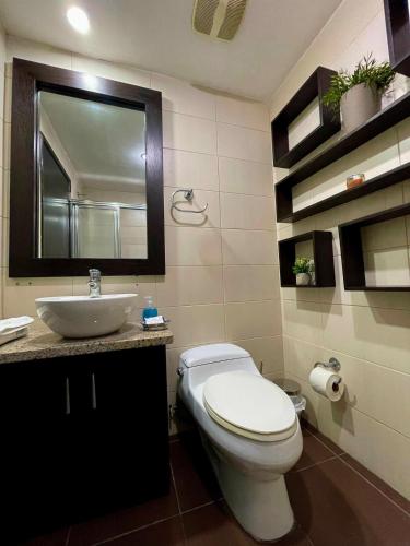 a bathroom with a toilet and a sink and a mirror at Ecuabook OmniHospital Torre Sol 702 in Guayaquil