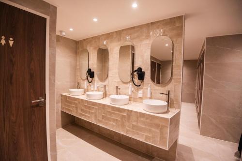 ein Bad mit 3 Waschbecken und 3 Spiegeln in der Unterkunft Cabins Hotel Amsterdam in Amsterdam