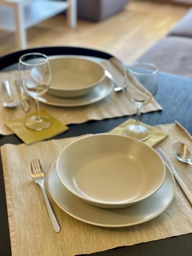 a table with two white plates and wine glasses at No̱410 City View Apartment & free parking in Krakow