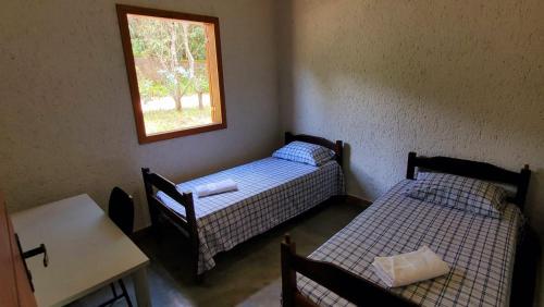 2 letti in una camera con tavolo e finestra di Casa Rústica Próxima ao Distrito de Milho Verde, 3 QUARTOS - São Gonçalo do Rio das Pedras, Serro a Sêrro