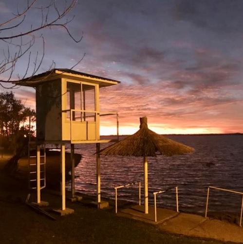 a lifeguard tower with a straw umbrella and the water at IRUPÉ APART HOTEL in Federación
