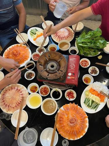 a group of people sitting around a table with food at Mây home Trạm Tấu bungalow in Ya Ló