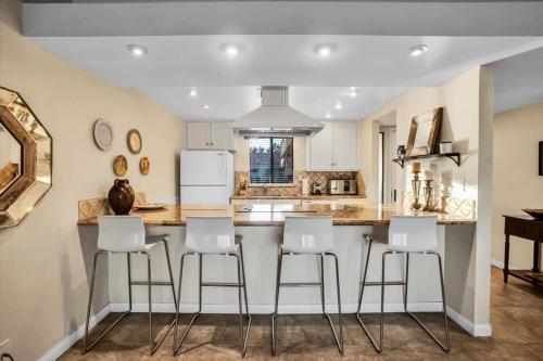 a kitchen with a bar with white stools at PD Resorter 2BR with Golf course views in Palm Desert
