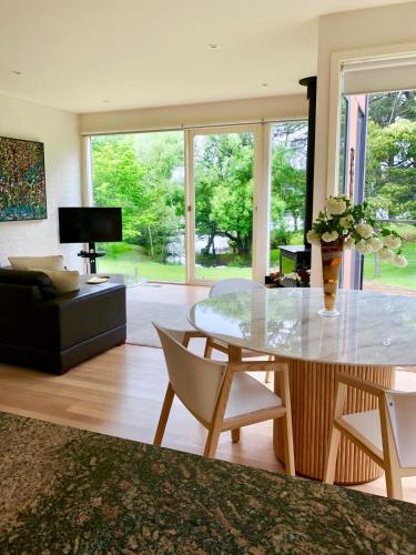 a living room with a glass table and chairs at Lake Daylesford Villa2 Lake frontage pet friendly in Daylesford