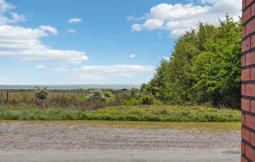 a brick wall next to a field with trees at Lovely House With A View Of The Limfjord in Øsløs
