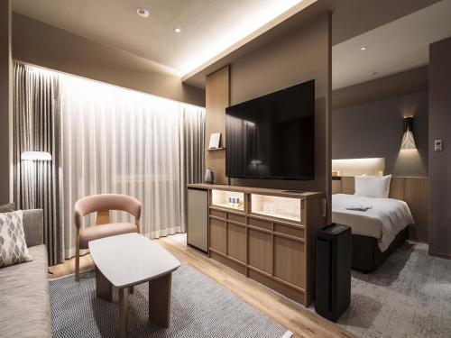 a hotel room with a bed and a flat screen tv at Richmond Hotel Obihiro Ekimae in Obihiro