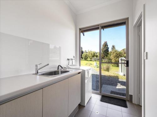 a white kitchen with a sink and a window at The Deck - Margaret River NEW in Margaret River Town