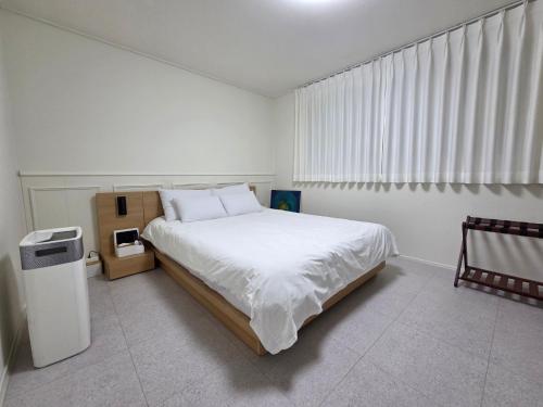 a white bedroom with a bed and a window at Dodam Stay in Seoul