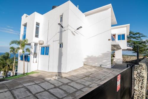 a white house with blue windows at Beautiful ocean and mountain view villa in Gaspar Hernández