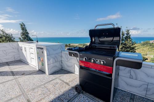 a grill on a patio with the ocean in the background at Beautiful ocean and mountain view villa in Gaspar Hernández
