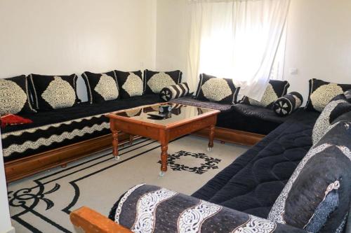 a living room with black couches and a coffee table at Appartement vue panoramique sur mer Avec Climatisation! à 5 minutes à pied de la Plage ! à environ 6 minutes en voiture du Centre d'Agadir et à 10 minutes en voiture de Taghazout ! in Agadir