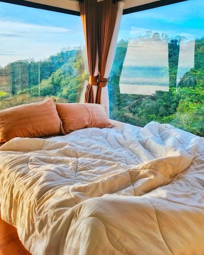 an unmade bed in front of a large window at Villane Tumpeng Menoreh in Giripurno
