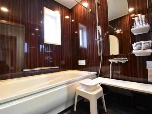 a bathroom with a tub and a sink and a stool at Inn光楽縁 in Okayama