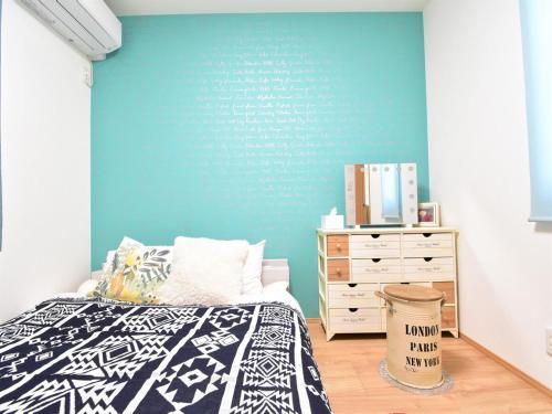 a bedroom with a bed and a blue wall at Inn光楽縁 in Okayama
