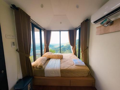 a bedroom with a bed with a large window at Villane Tumpeng Menoreh in Giripurno