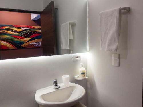 une salle de bain blanche avec un lavabo et un miroir dans l'établissement Apartasuite en el Corazón del Eje Cafetero, à Pereira