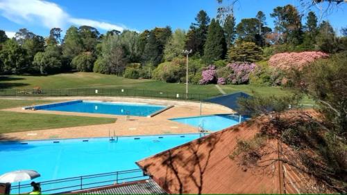 a large swimming pool in a park with trees at Brechin Cottage in Blackheath