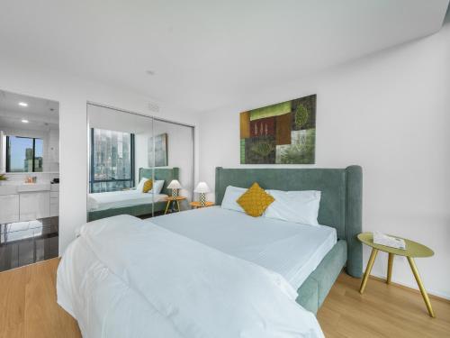 メルボルンにある37th Floor City Views Luxury Apartment and Parkingの大きなベッドとバスルームを備えた白い寝室