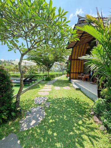 a garden with a tree next to a building at Adil Villa & Resort in Ubud
