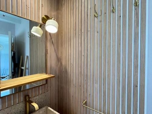 a bathroom with a wooden wall with a mirror and a sink at Charmante maison proche plage à Groix, 2 chambres - FR-1-813-3 in Groix