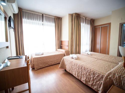 a hotel room with two beds and a window at Hotel Castilla in Albacete