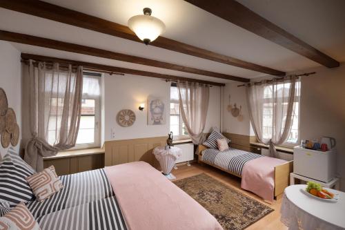 a bedroom with two beds and a couch and windows at Hotel Restaurant Syrtaki in Gernsbach