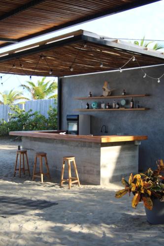 a outdoor kitchen with stools and a counter with a bar at Las Hamacas in Canoas De Punta Sal