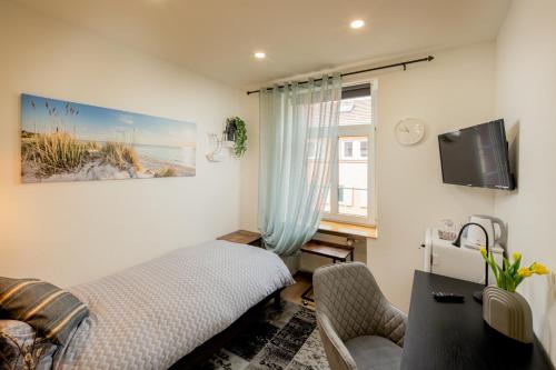 a bedroom with a bed and a tv and a window at Hotel Restaurant Syrtaki in Gernsbach
