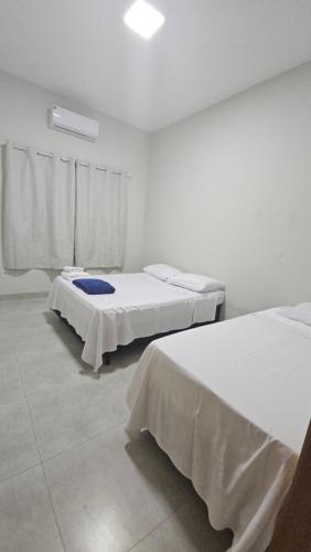 two beds in a room with white walls at Casa Nova 03 in Primavera do Leste
