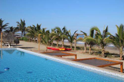 a swimming pool next to a beach with palm trees at Las Hamacas in Canoas De Punta Sal