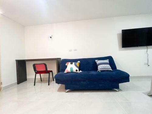 a blue couch in a living room with a red chair at Económico apartamento en el centro de la ciudad in Medellín