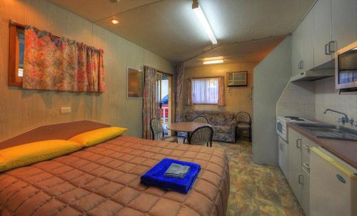 a small bedroom with a bed and a kitchen at Highway Tourist Village in Narrabri
