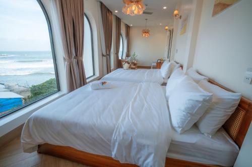 a bedroom with a white bed with a large window at Sunsea House-Đá Đĩa Phú Yên in Tuy An
