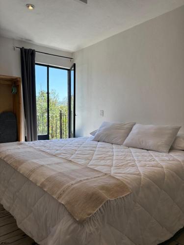 a large bed in a bedroom with a large window at Santa Noche Loft & Spa in San Miguel de Allende