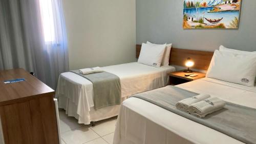 a hotel room with two beds and a desk at Pousada Porto Rio in Parnaíba