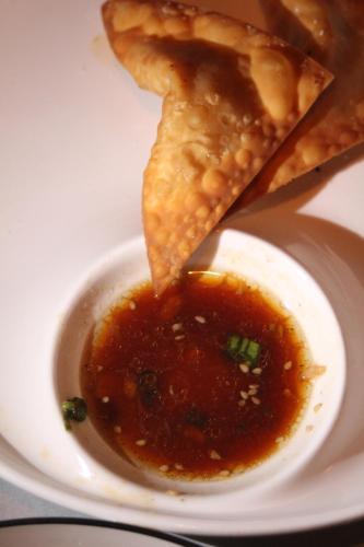 a plate with a bowl of dipping sauce and some food at Las Hamacas in Canoas De Punta Sal