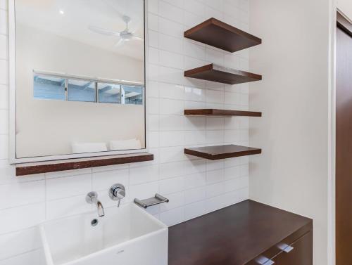 a white bathroom with a sink and a mirror at Luxury Oceanfront Haven with a Private Rooftop Spa in Kingscliff